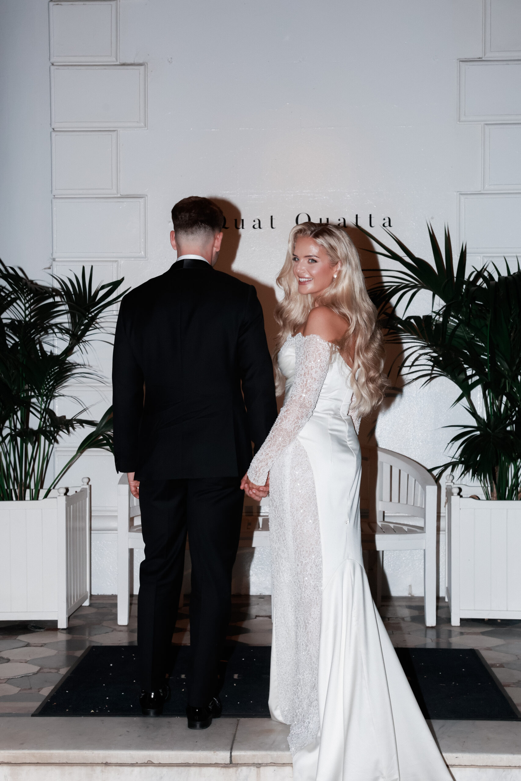 Back angle of a bride and groom at their wedding celebration. Bride turns to face camera. 
