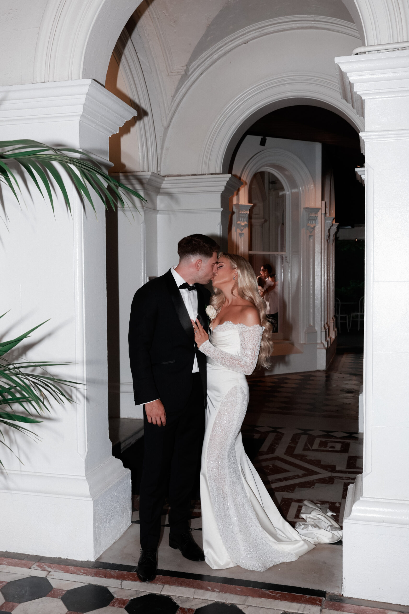 bride and groom kissing under ncurved arches 