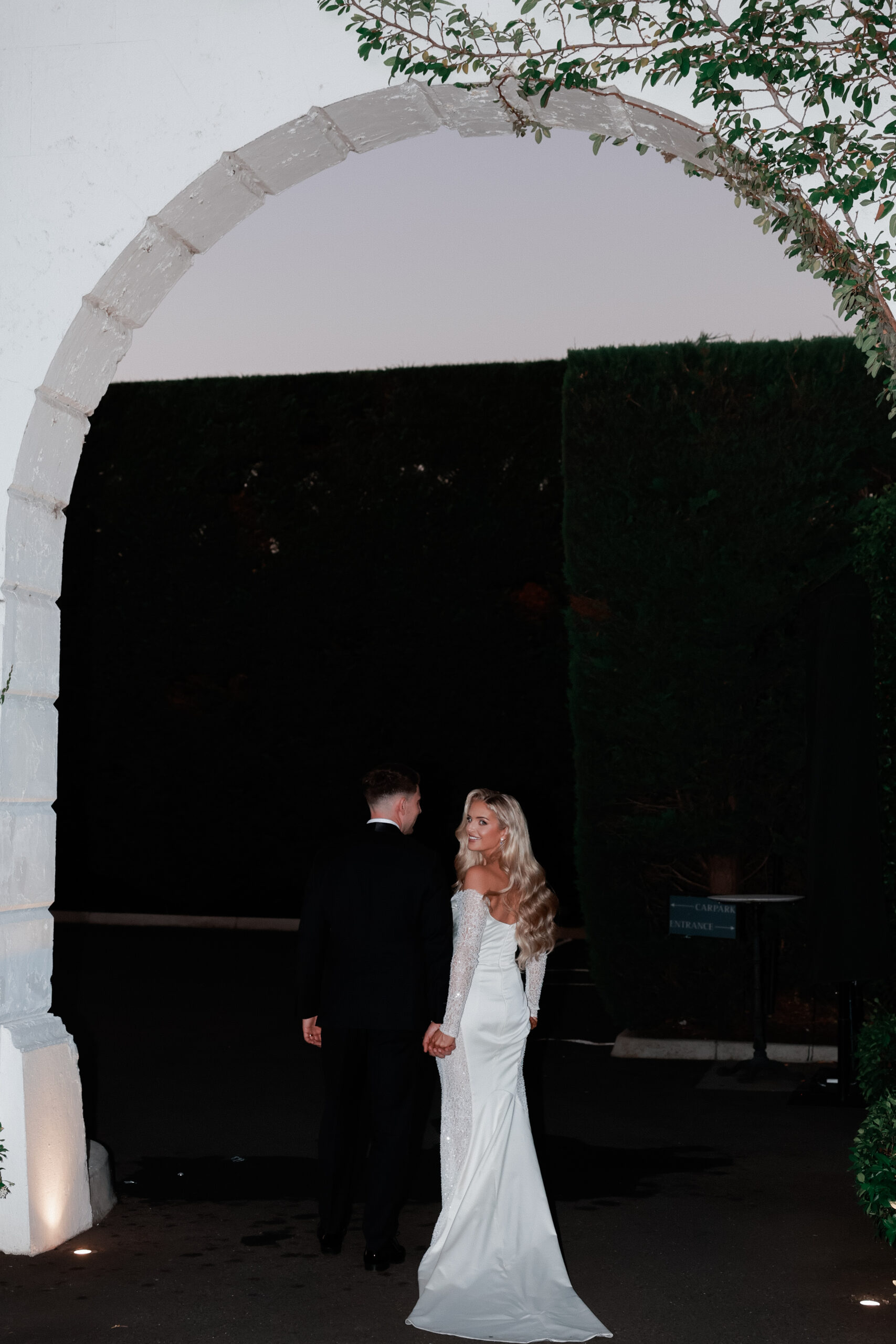 Bride and groom back angle photo, bride turns over and smiles at camera. 