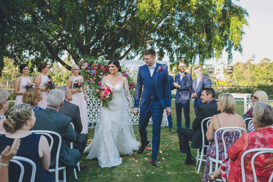 bride and groom walking down aisle together photo off the shoulder lace wedding dress