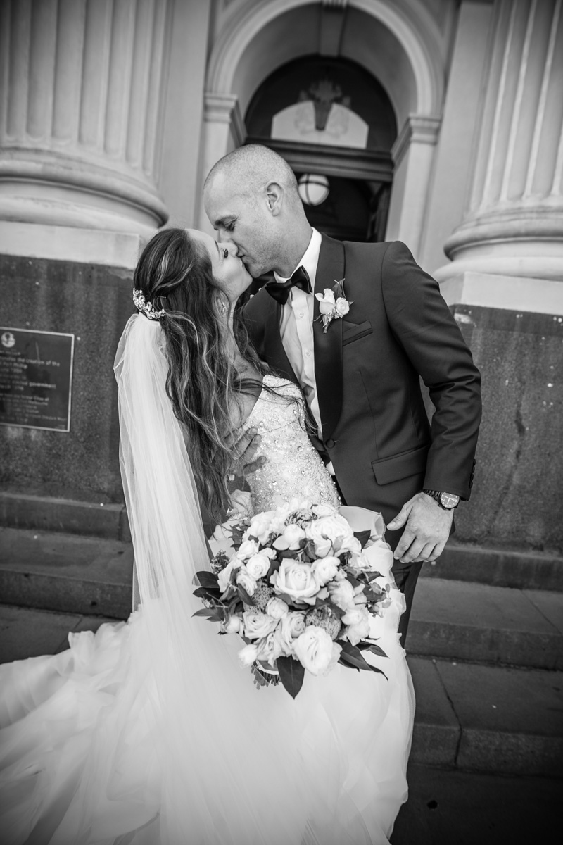 black and white photo bride and groom kissing with veil