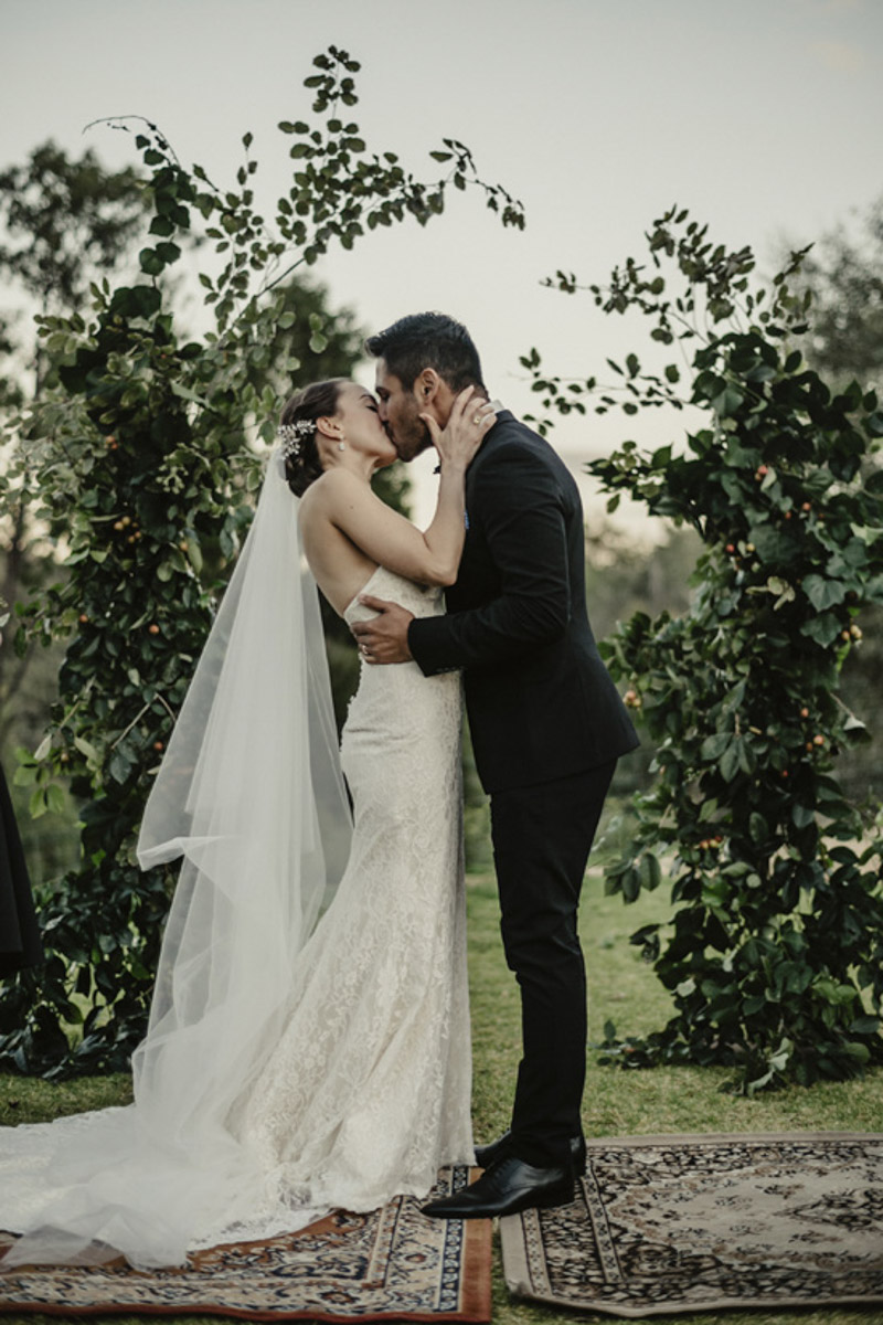 bride and groom kissing ceremony photo under arbour
