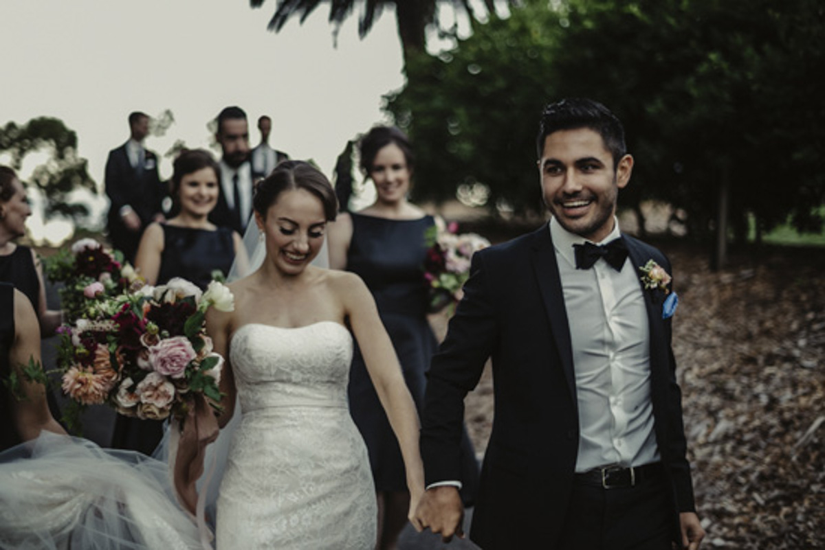 bride and groom weddingwalking photo with bridal party behind